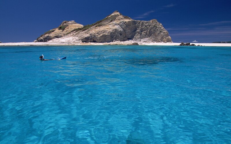 Snorkeler near rocky island
