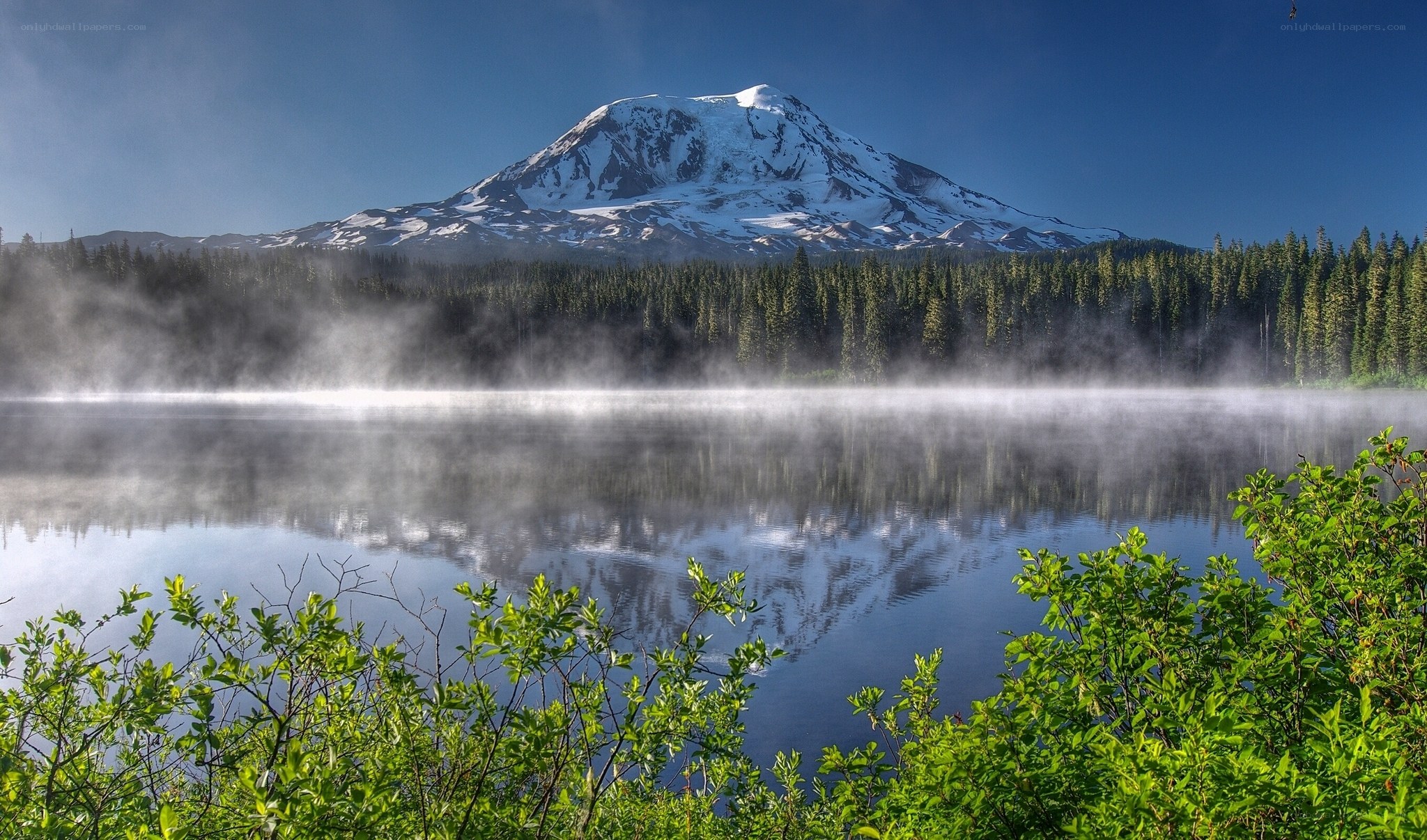 Snow-capped mountain reflected in a misty lake