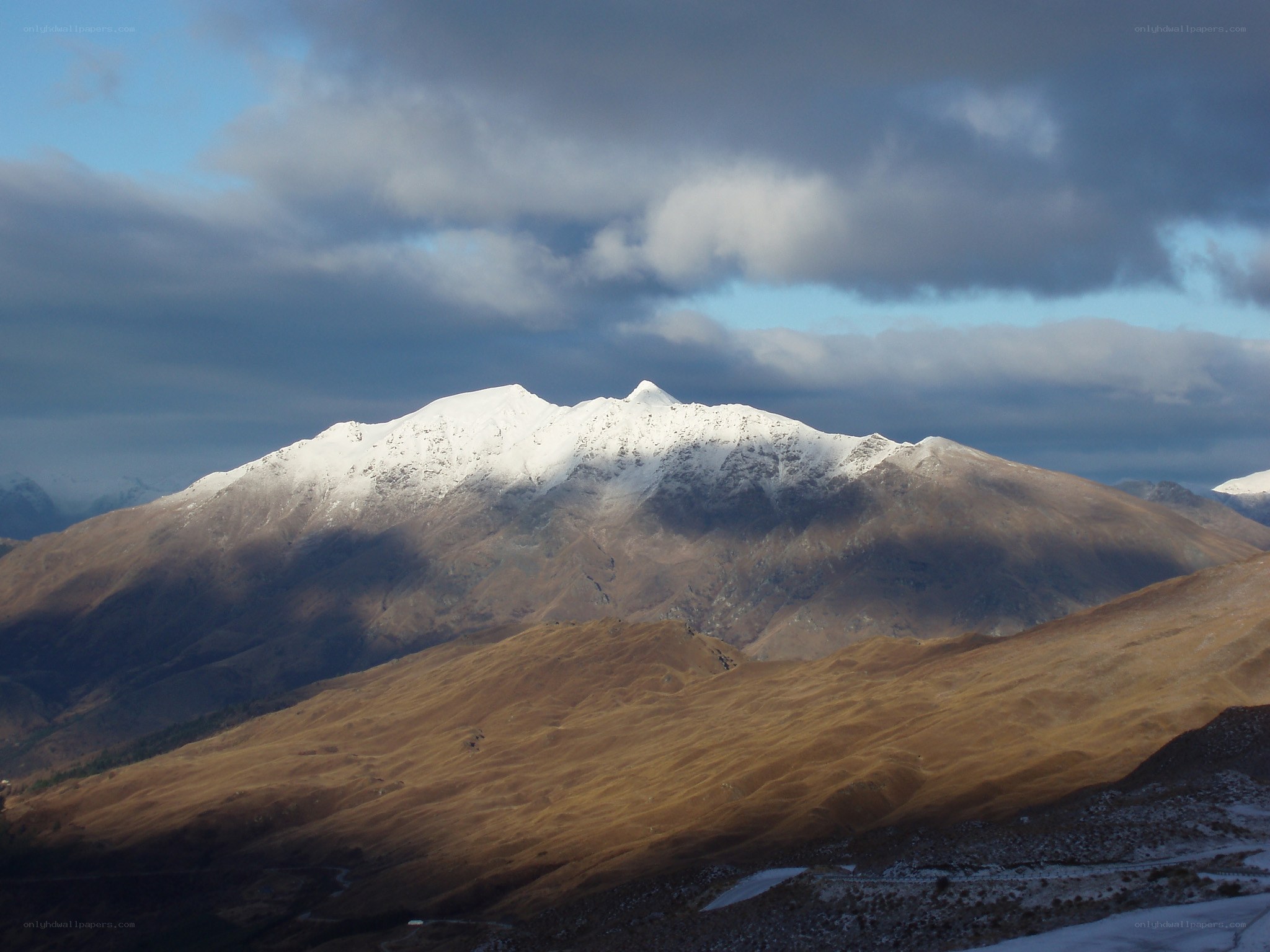 Snow-capped mountain under cloudy sky
