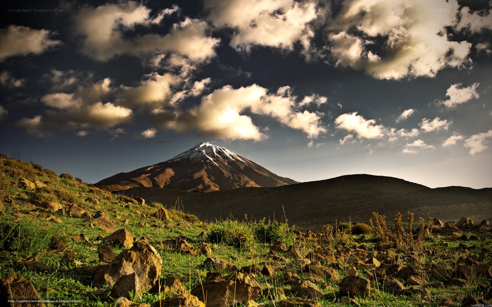Snow-capped mountain under cloudy sky