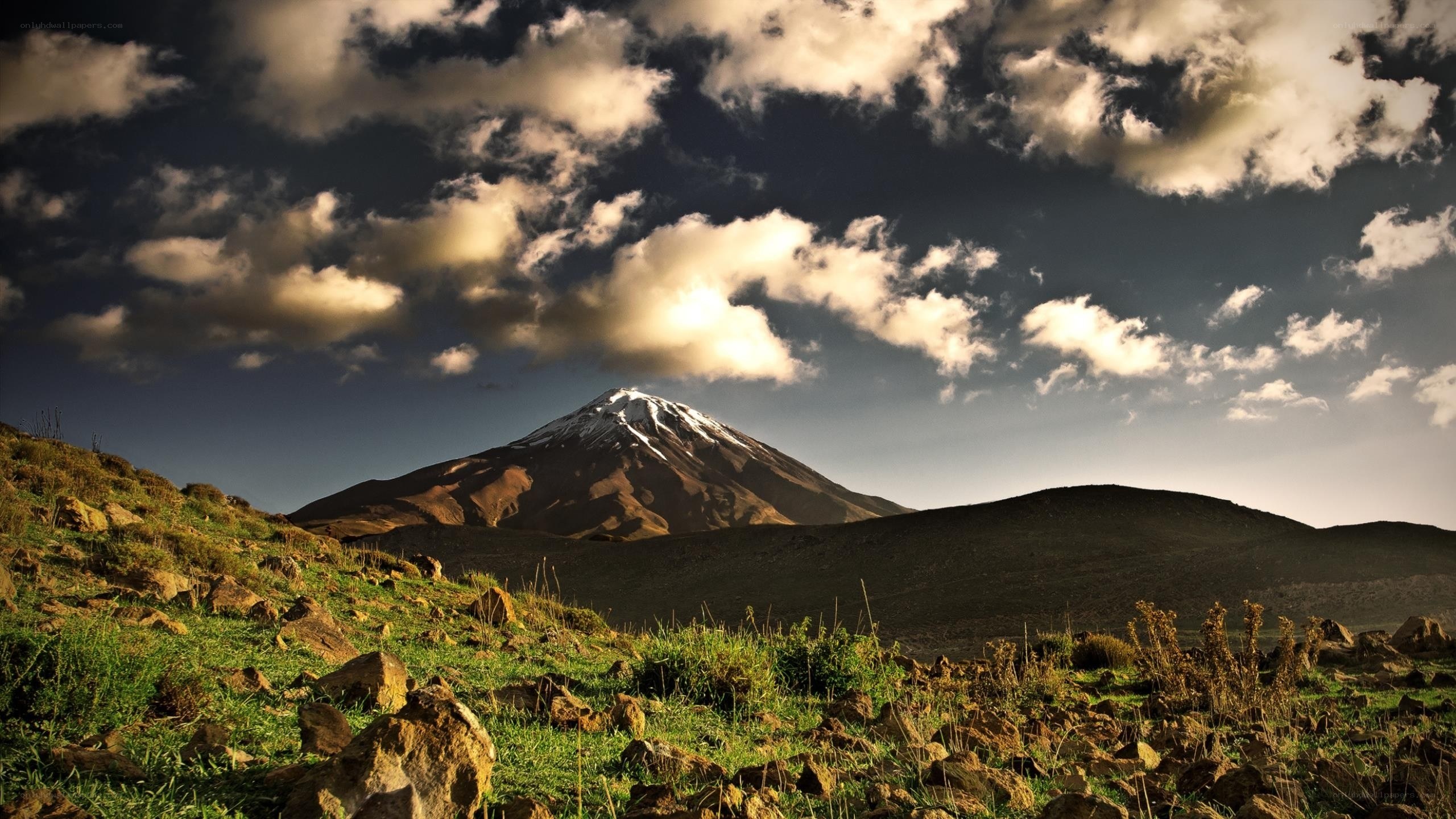 Snow-capped mountain under cloudy sky