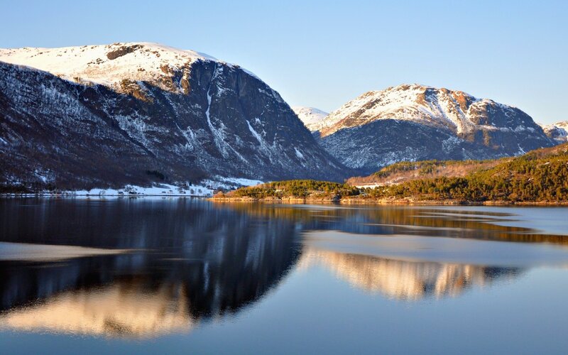 Snow-capped mountains reflect in a calm lake