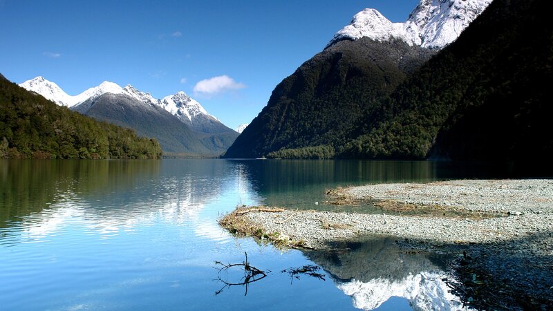 Snow-capped mountains reflect in a calm lake