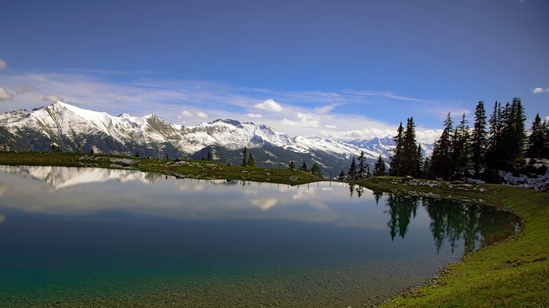 Snow-capped mountains reflect in a calm lake