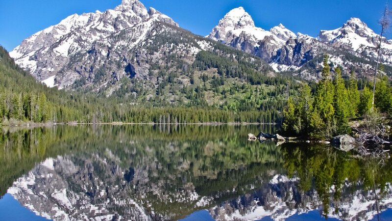 Snow-capped mountains reflect in a calm lake