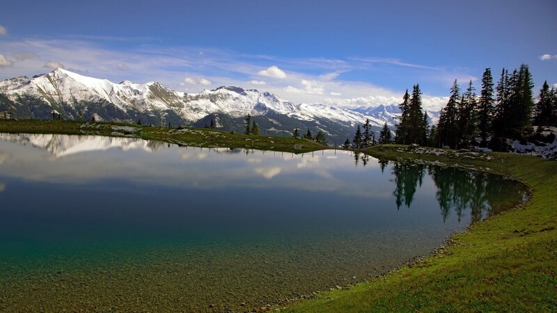 Snow-capped mountains reflect in a calm lake