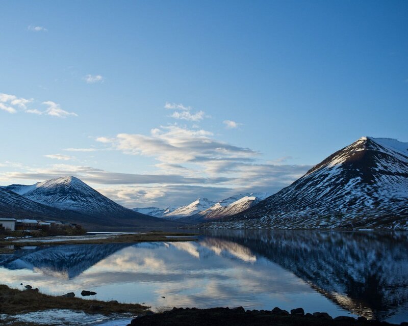 Snow-capped mountains reflect in a calm lake