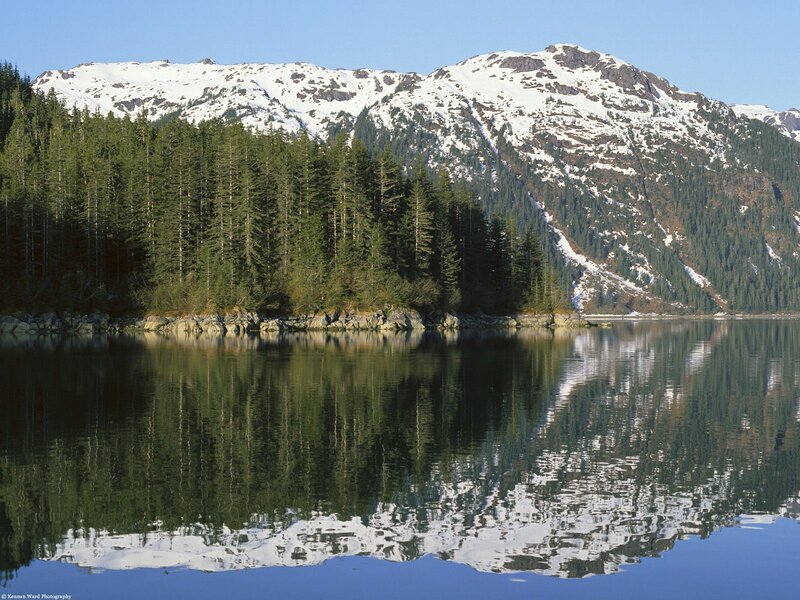 Snow-capped mountains reflect in calm lake