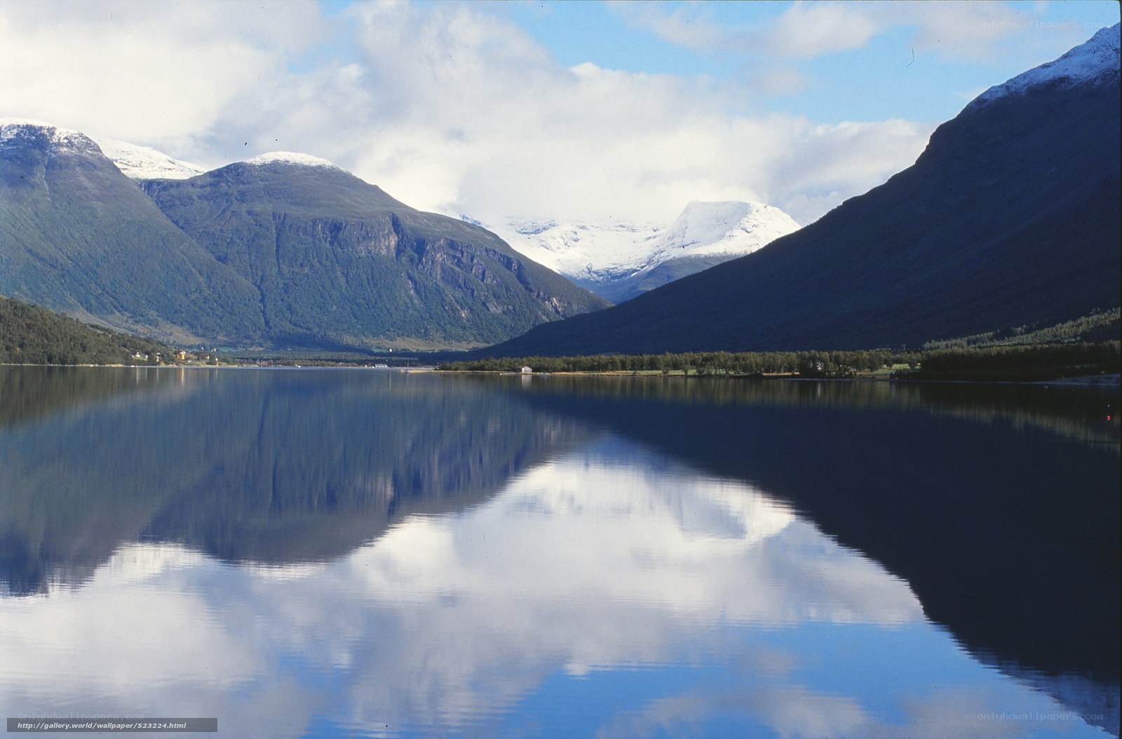 Snow-capped mountains reflect in calm lake