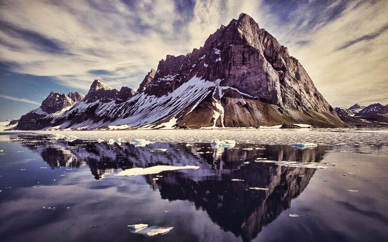 Snow-capped mountains reflect in calm water