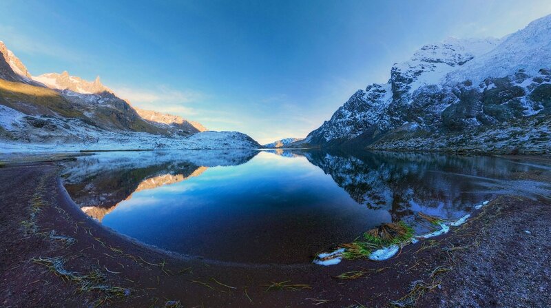 Snow-capped mountains reflect in lake