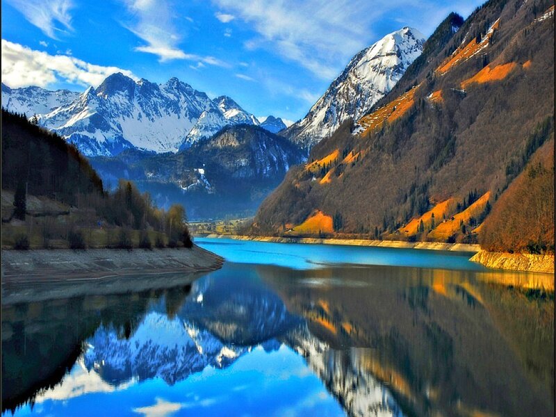 Snow-capped mountains reflect in lake