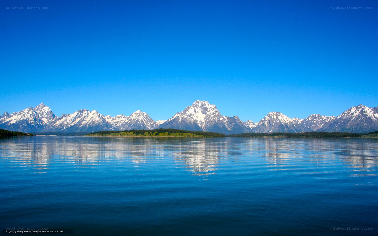Snow-capped mountains reflect in lake