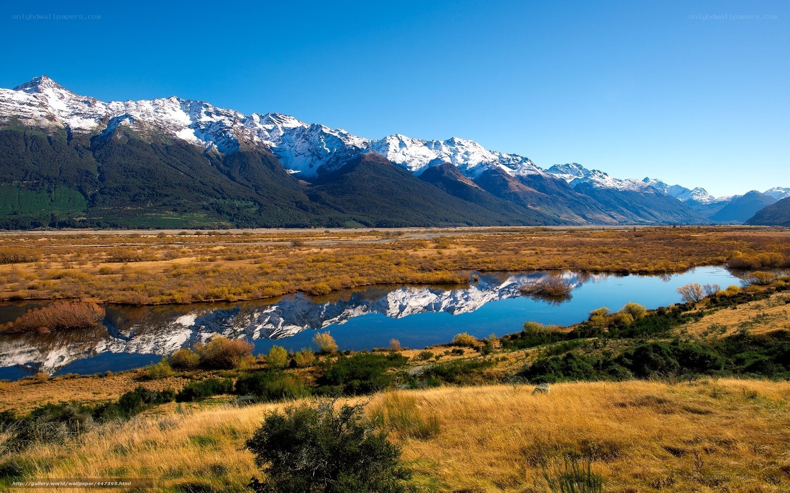 Snow-capped mountains reflect in river