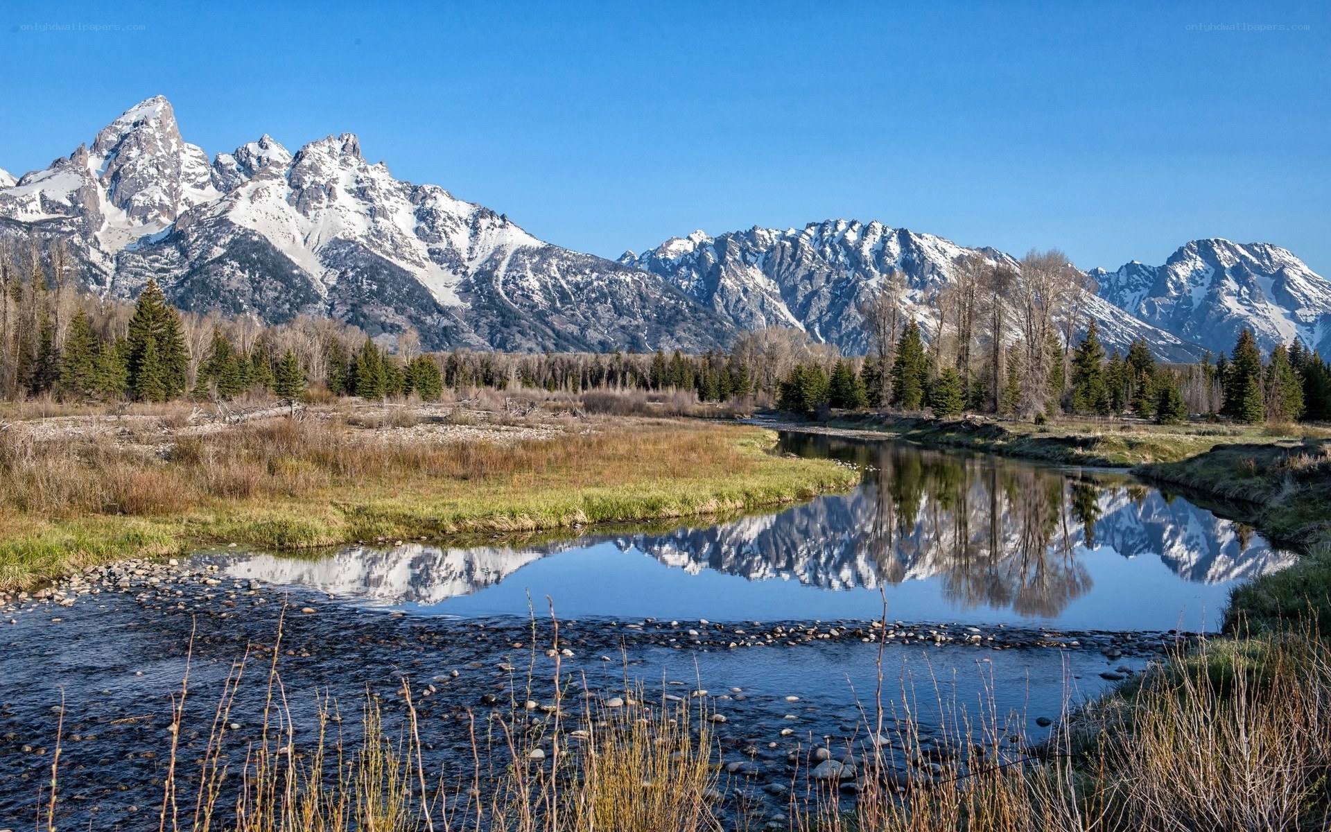 Snow-capped mountains reflect in river