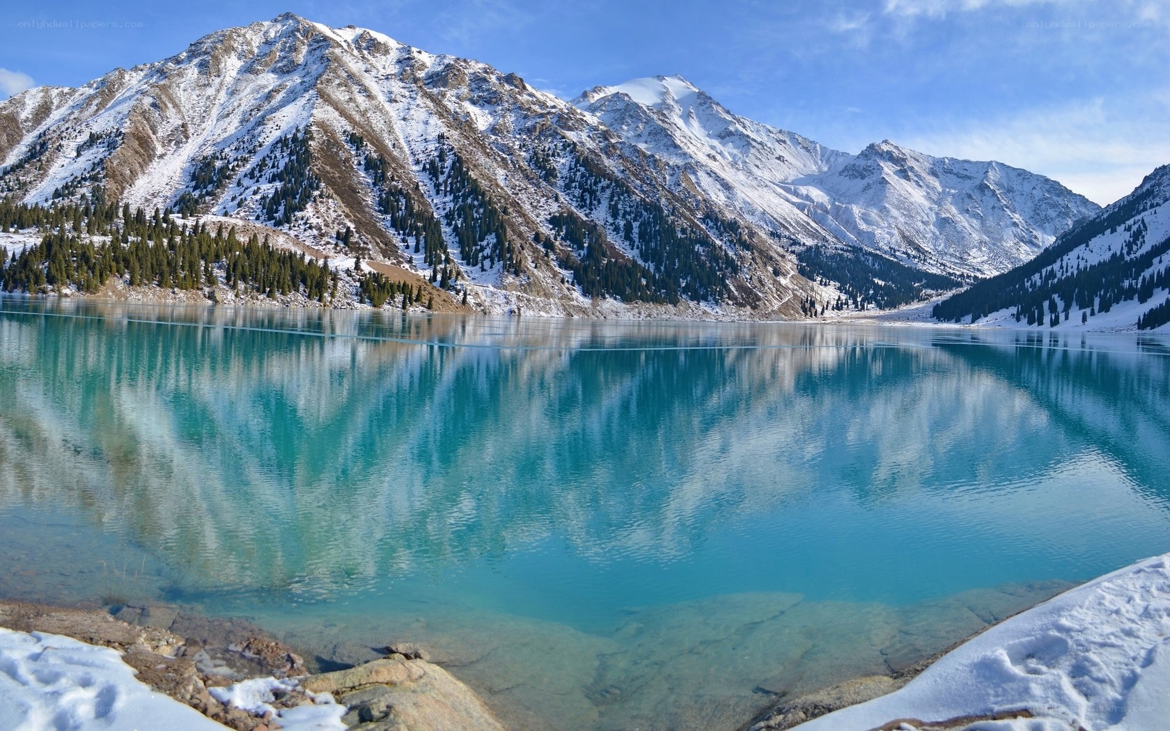 Snow-capped mountains reflect in turquoise lake