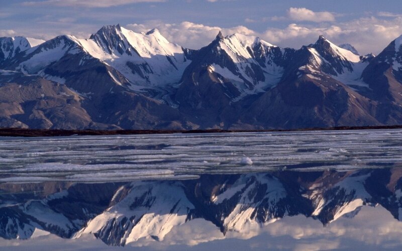 Snow-capped mountains reflected in ice