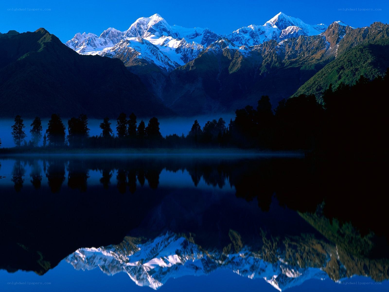 Snow-capped mountains reflected in lake
