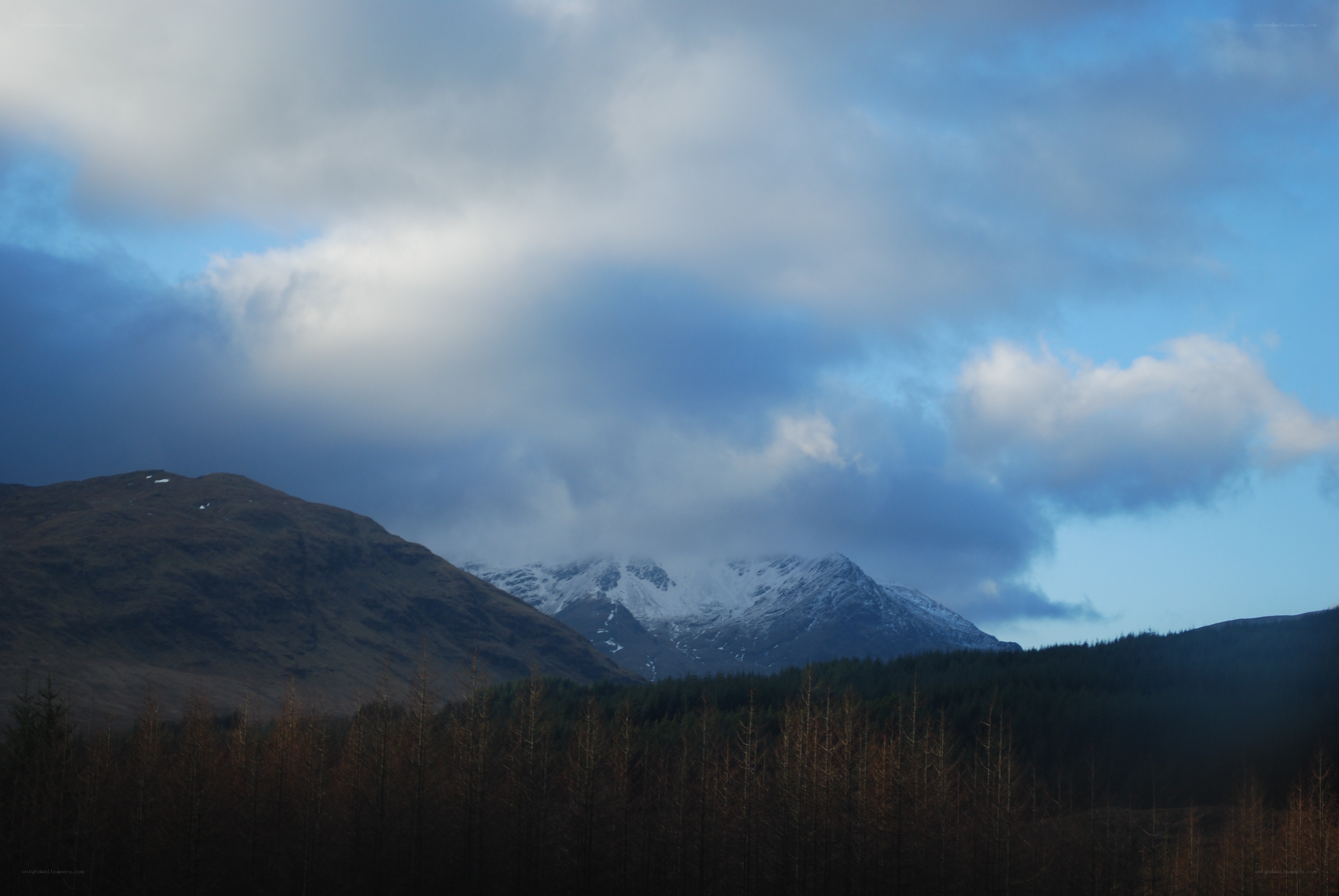 Snow-capped mountains under cloudy sky