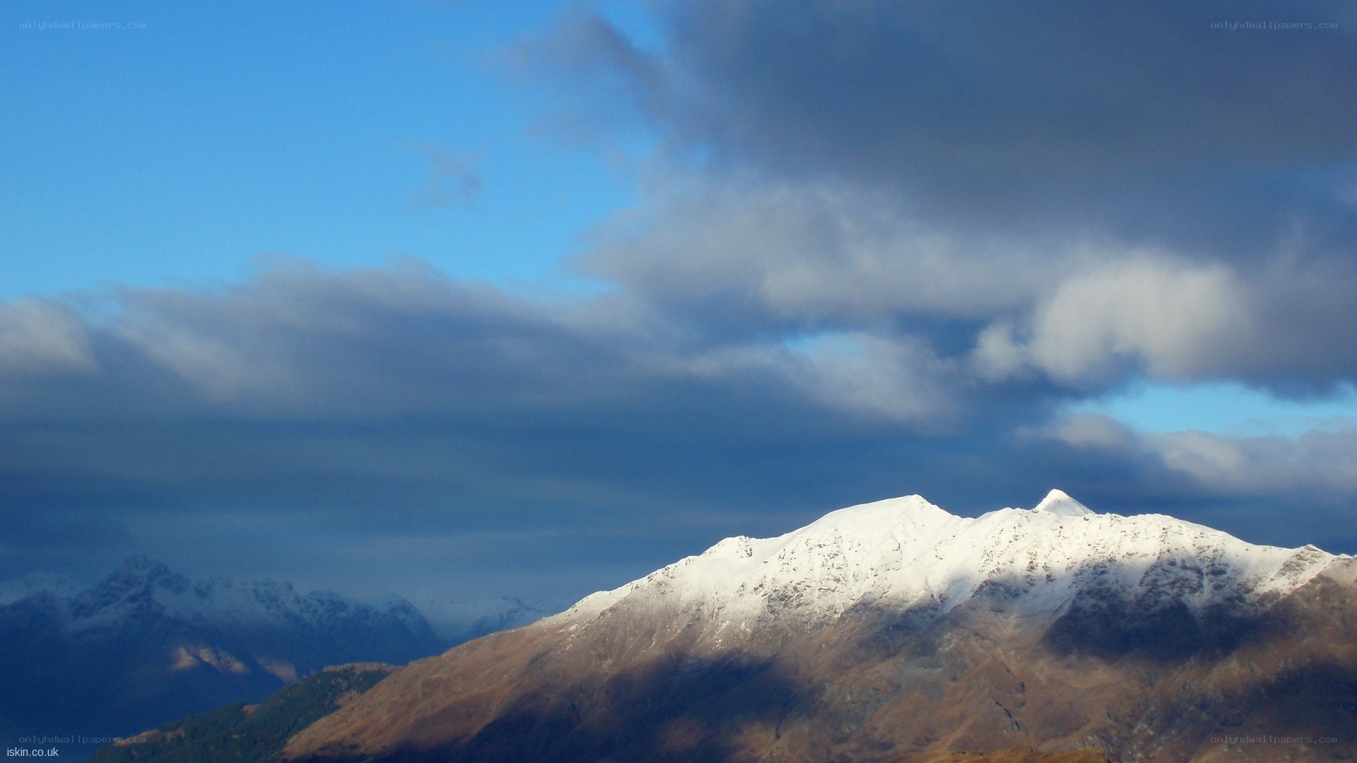 Snow-capped mountains under cloudy sky