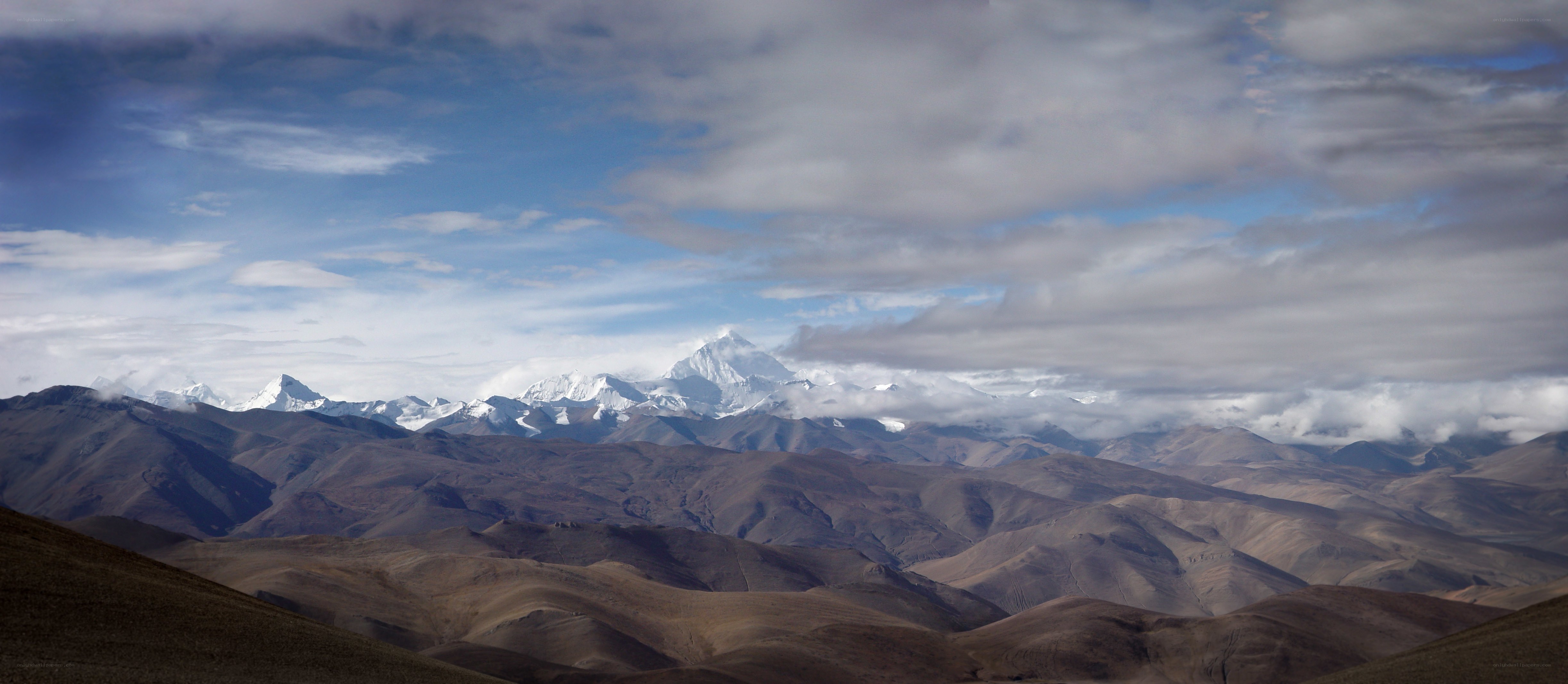 Snow-capped mountains under cloudy sky