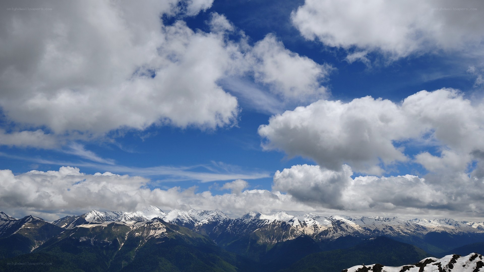 Snow-capped mountains under cloudy sky