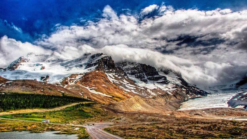 Snow-capped mountains under cloudy sky