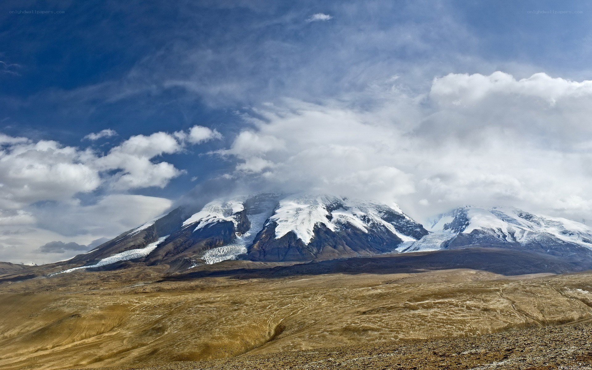 Snow-capped mountains under cloudy sky