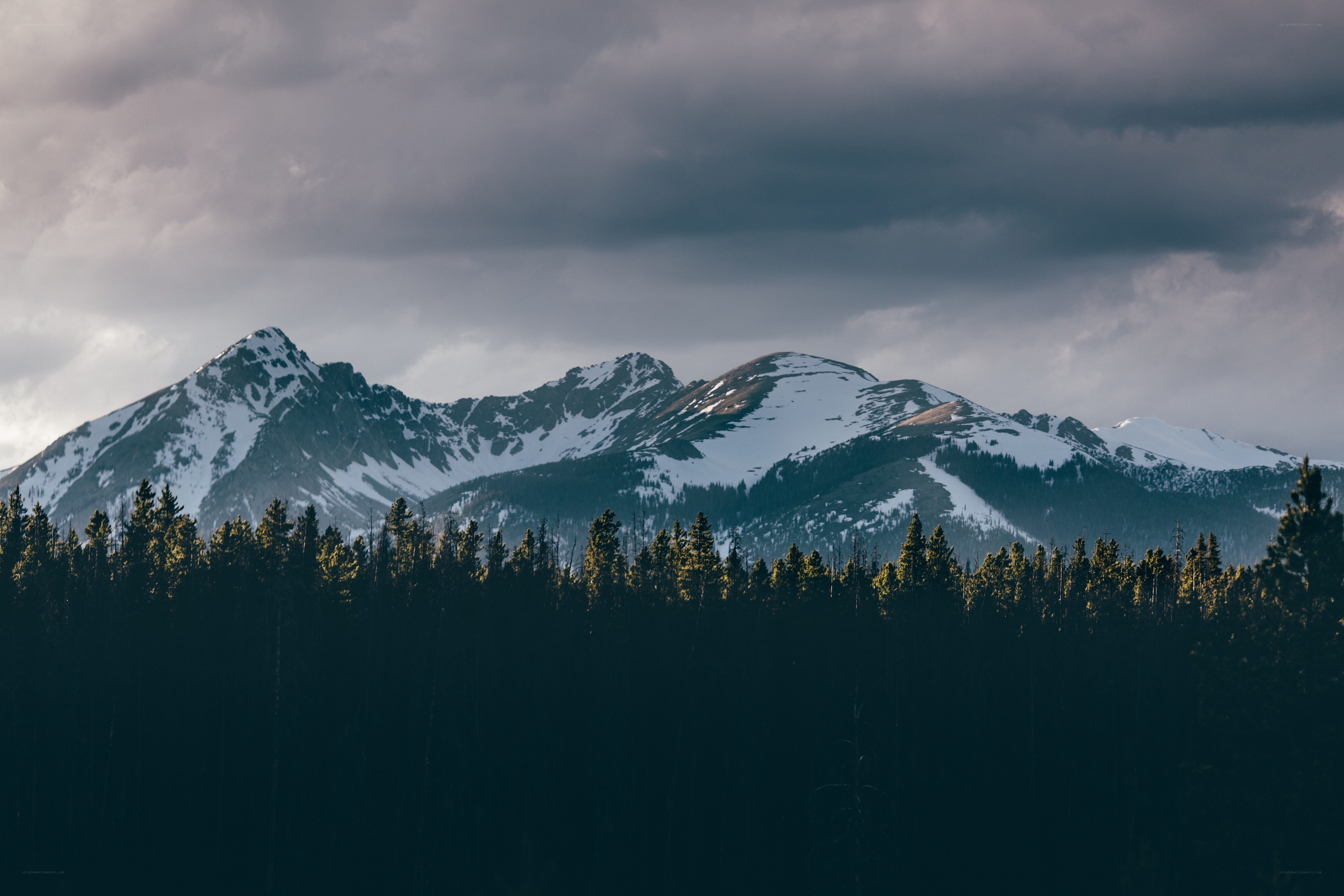 Snow-capped mountains under cloudy sky