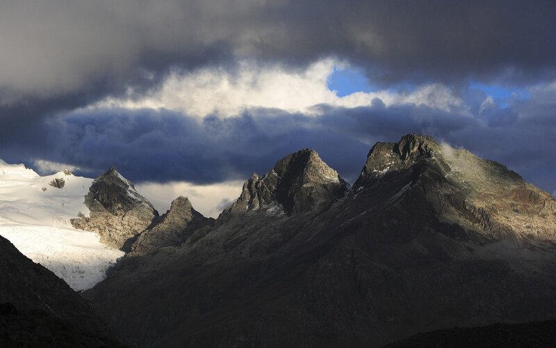 Snow-capped mountains under stormy sky
