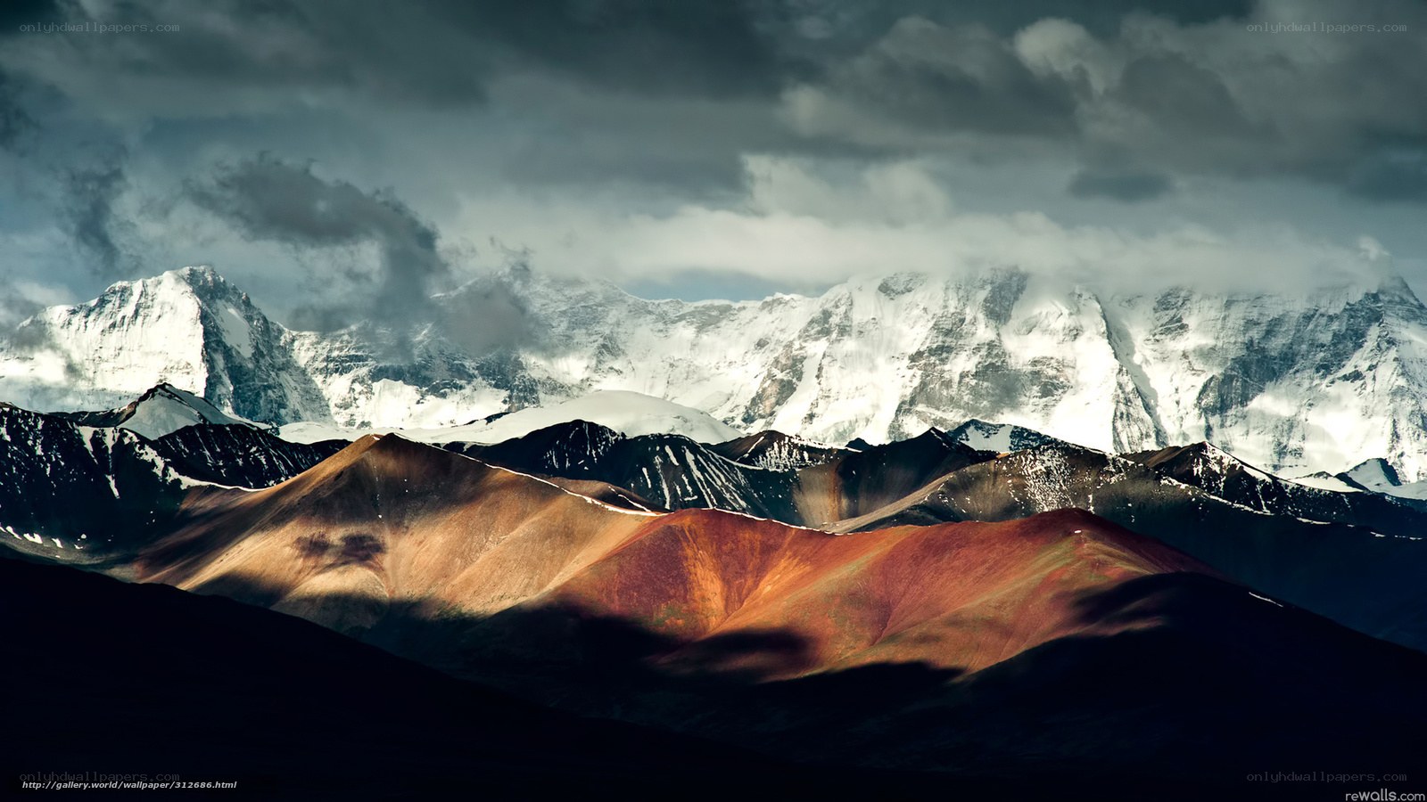 Snow-capped mountains under stormy sky