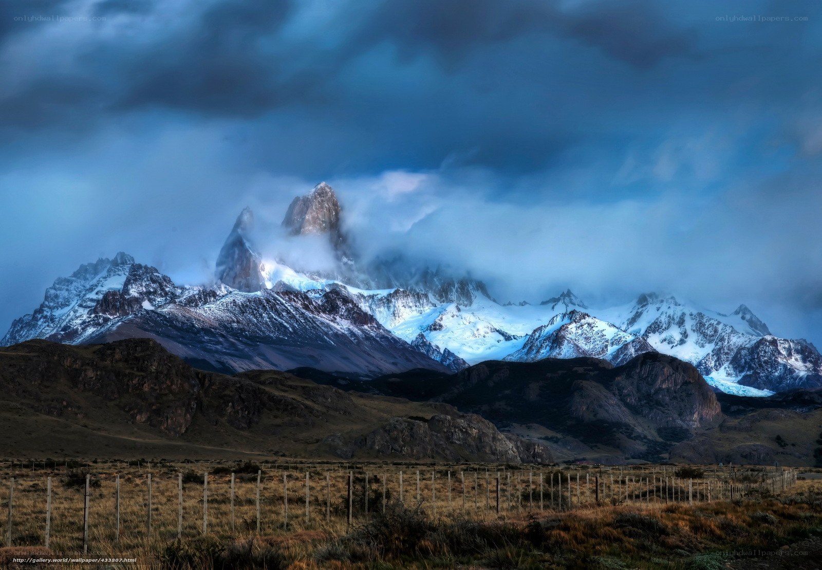 Snow-capped mountains under stormy sky