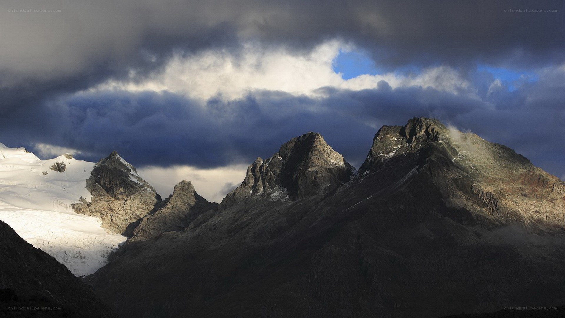 Snow-capped mountains under stormy sky