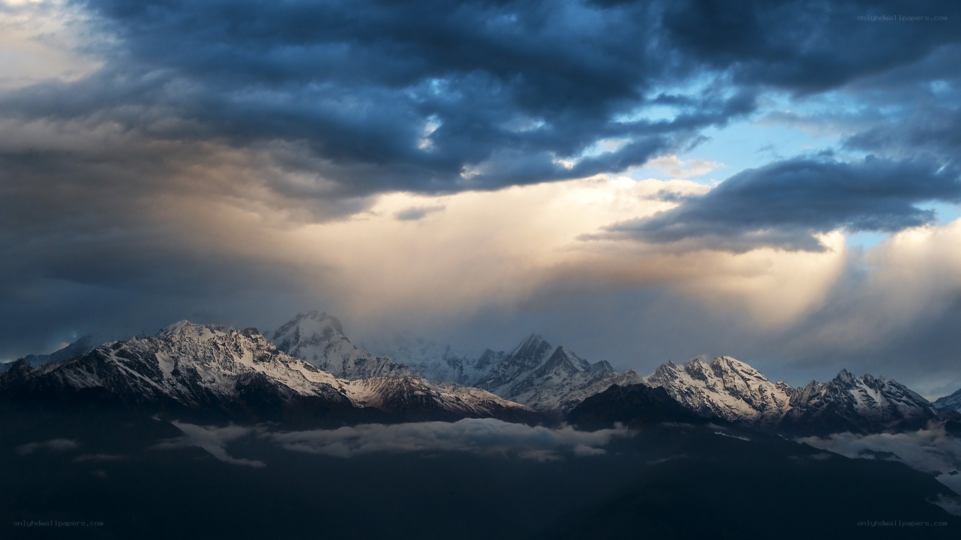 Snow-capped mountains under stormy sky
