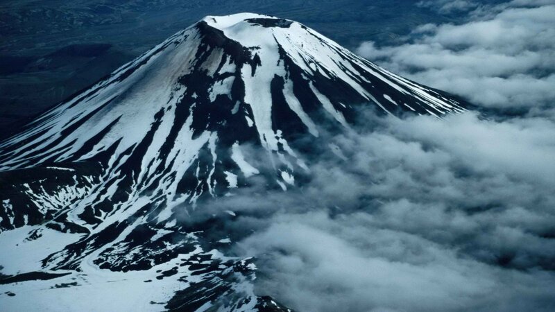 Snow-capped volcano above clouds