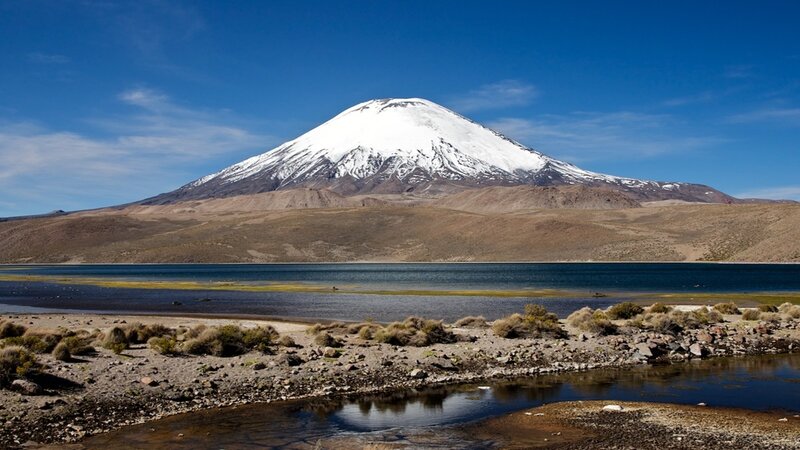 Snow-capped volcano by a lake