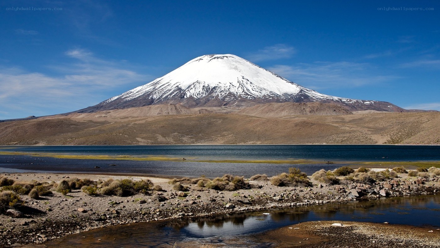 Snow-capped volcano by a lake