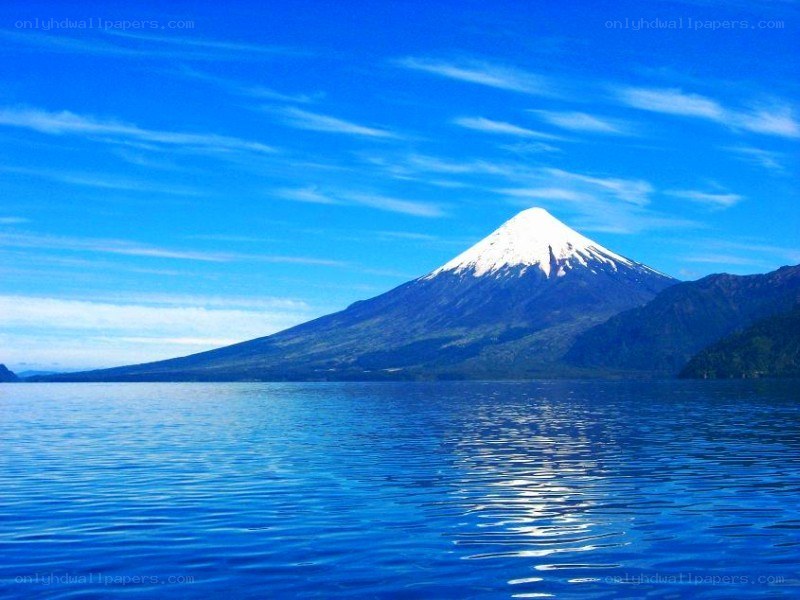 Snow-capped volcano by a lake