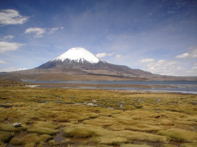 Snow-capped volcano by a lake