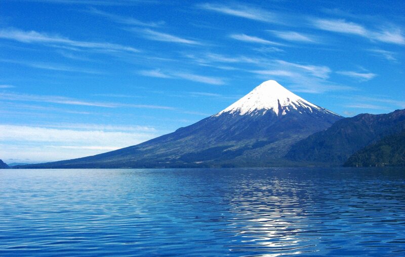 Snow-capped volcano by a lake