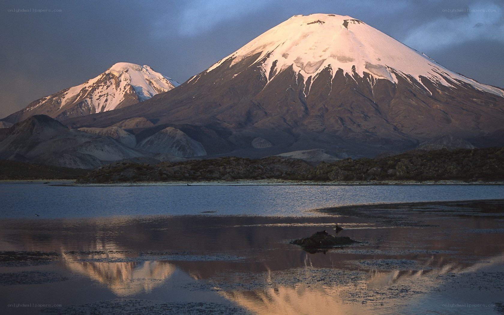 Snow-capped volcanoes reflected in lake