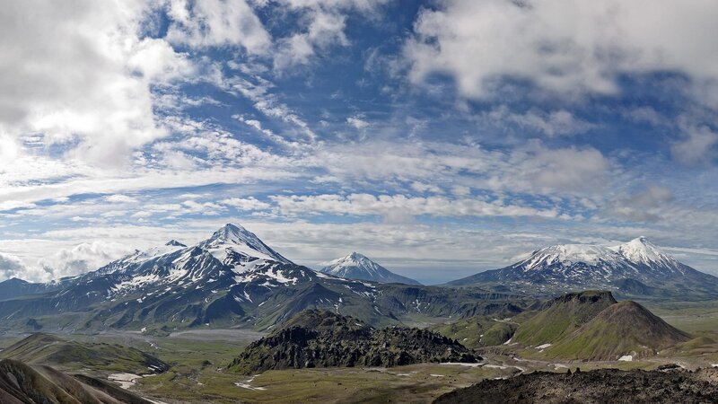 snow-capped volcanoes under cloudy sky