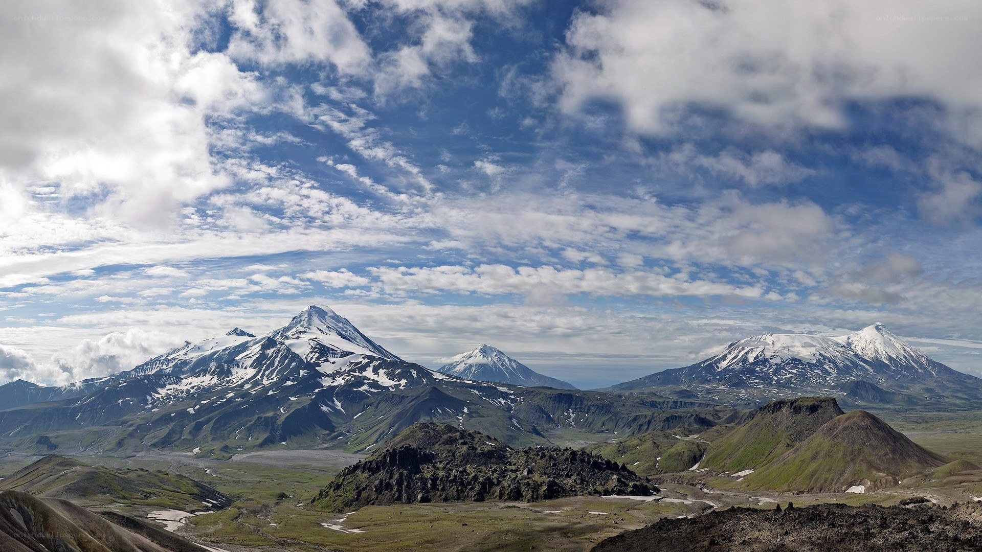 snow-capped volcanoes under cloudy sky