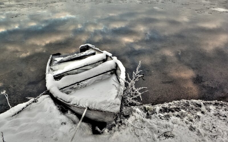 Snow-covered boat on frozen lake
