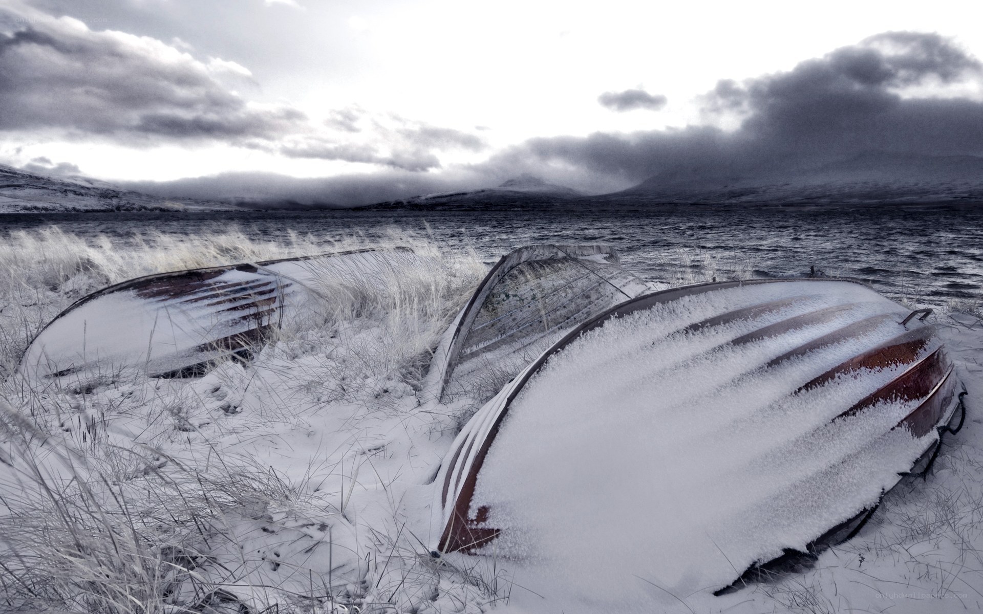 Snow-covered boats on a lake shore