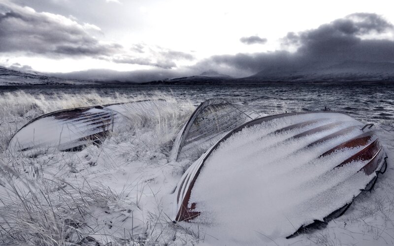 Snow-covered boats on a shore