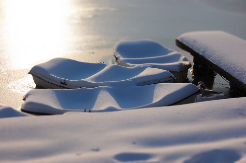 Snow-covered boats on frozen lake