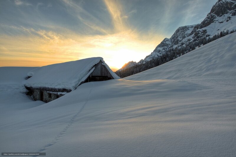 Snow-covered cabin at sunset