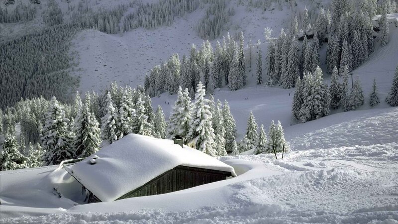 Snow-covered cabin in mountain valley