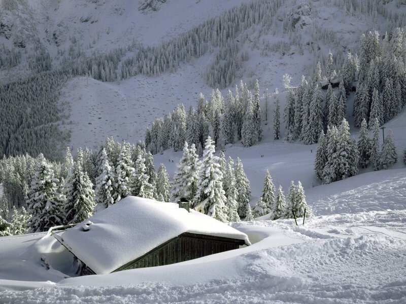 Snow-covered cabin in mountain valley